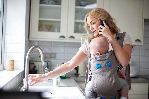 Woman holding baby while on her cell phone