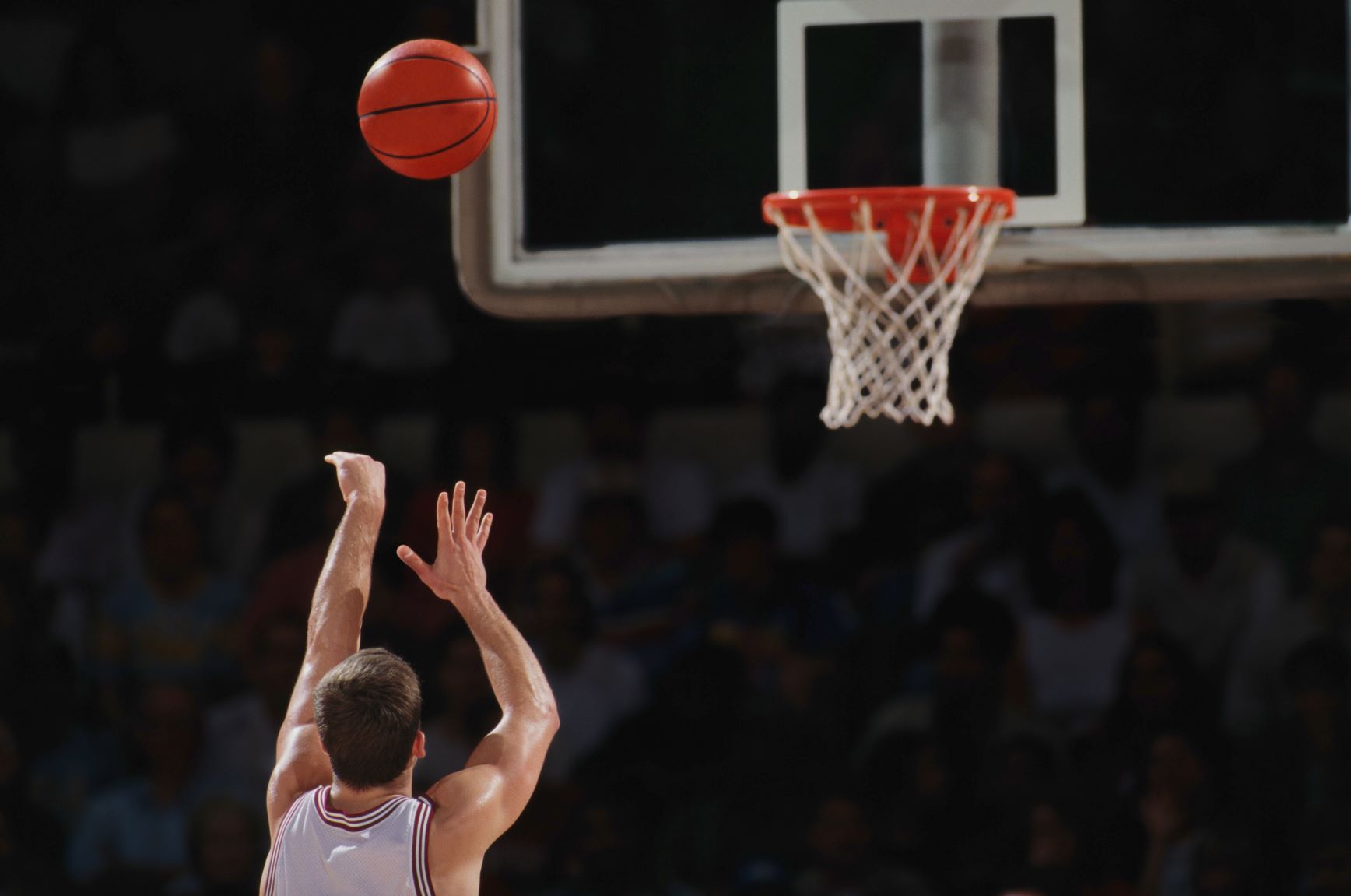 Basketball player throwing ball toward basket
