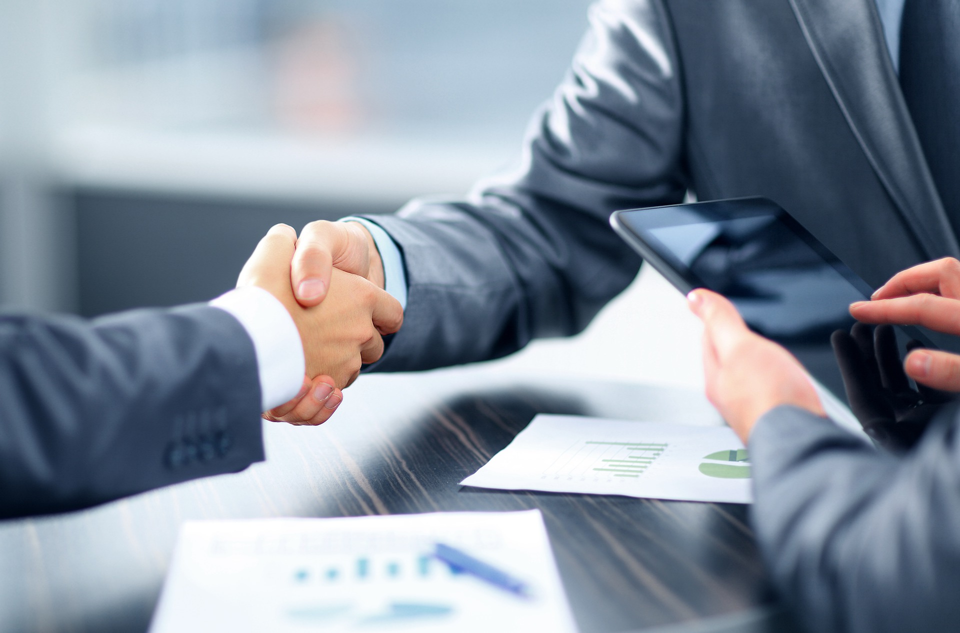 Two people shaking hands over paperwork
