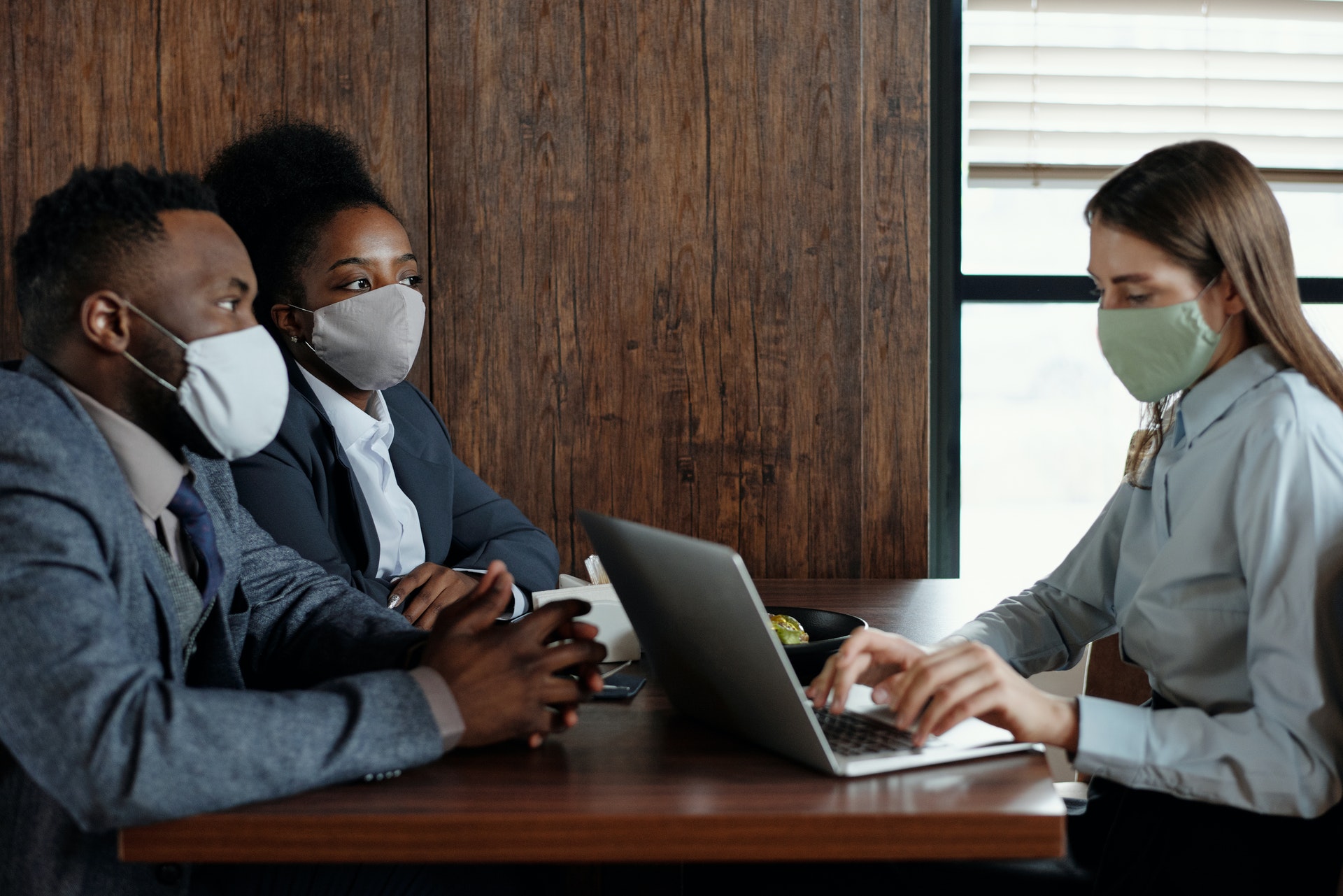 masked couple meeting with masked woman using laptop computer