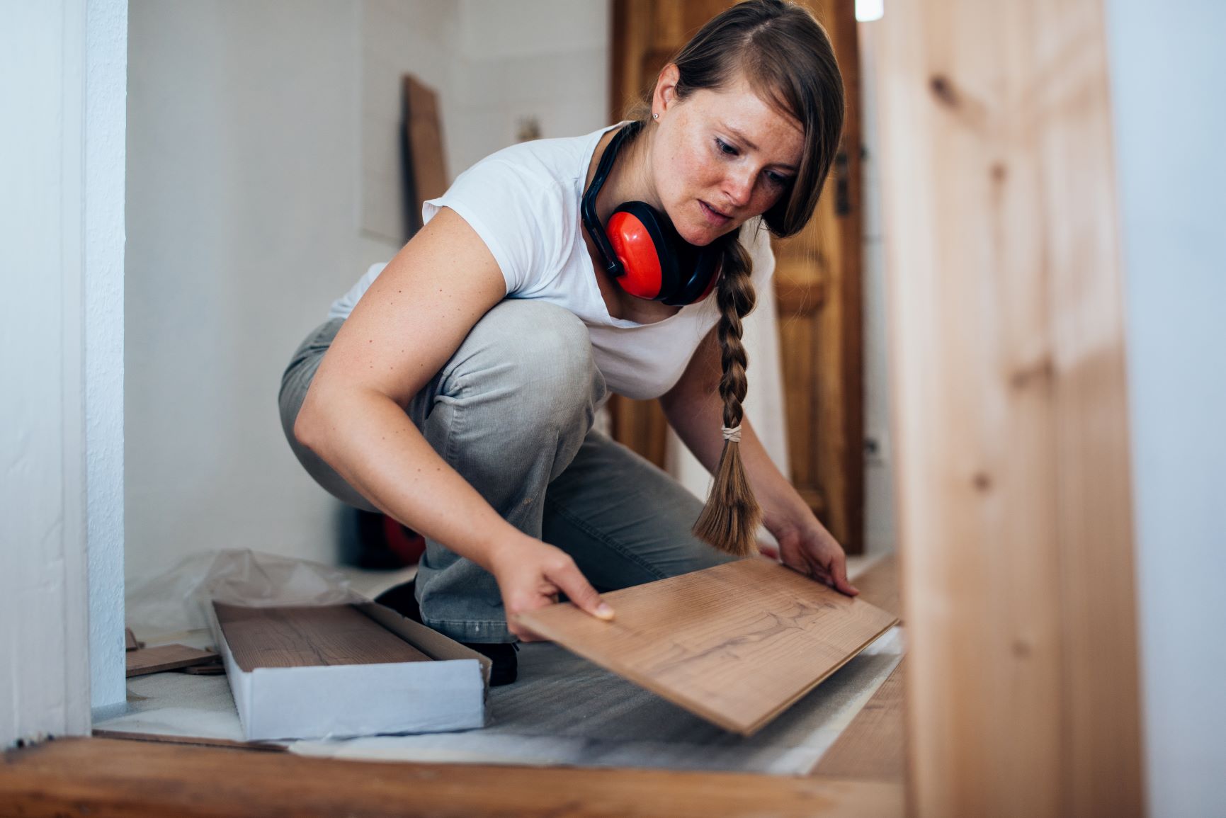 Woman placing wood board on floor.